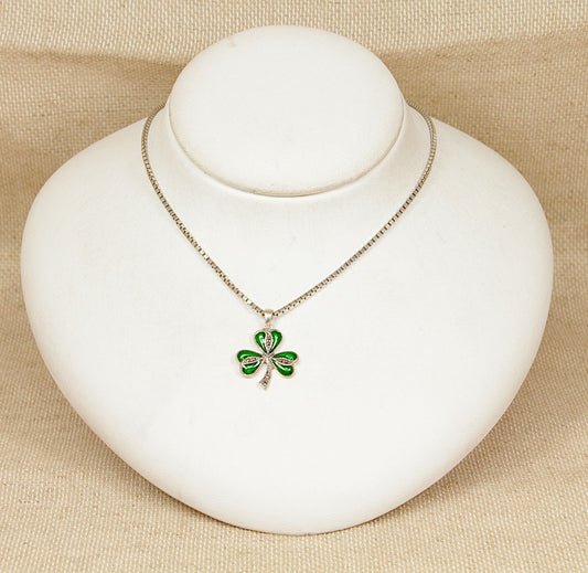 Irish green shamrock pendant  necklace on a white stand with a beige background