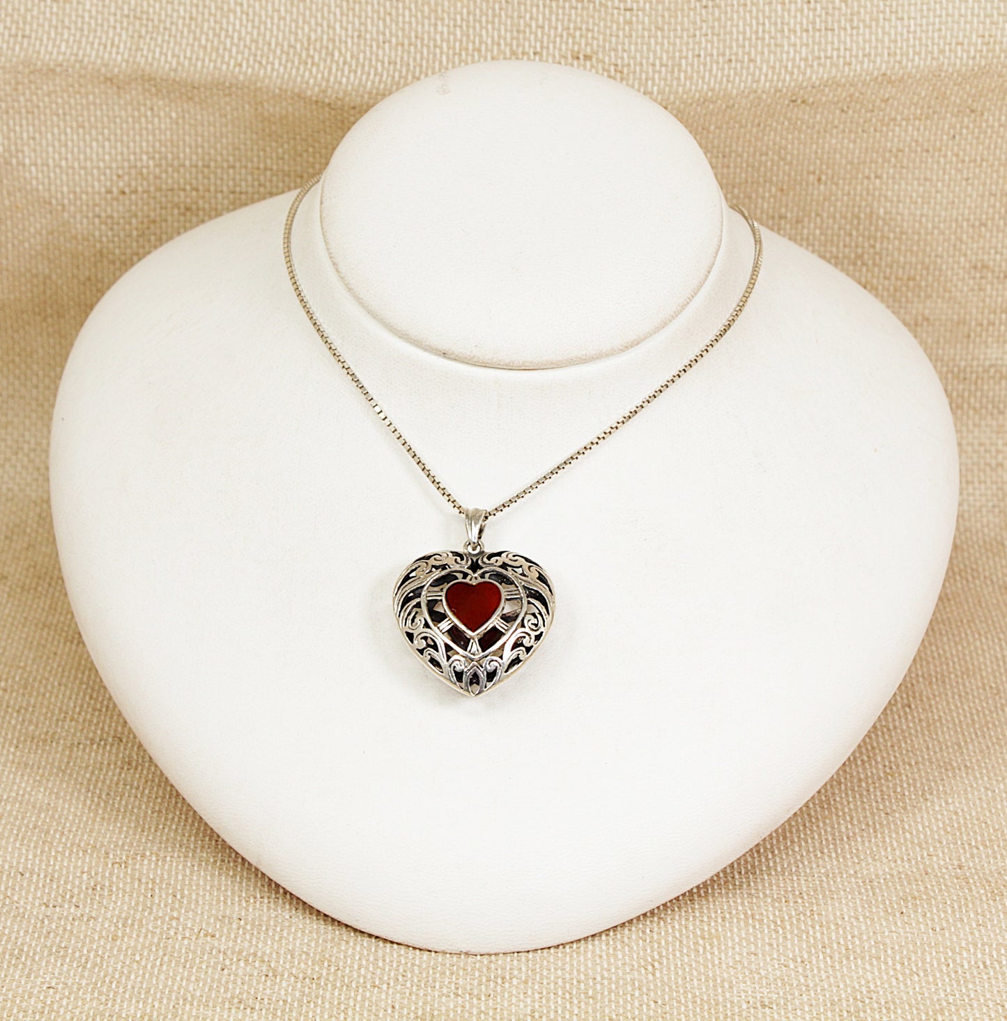Heart-shaped pendant necklace on a white bust against a beige background