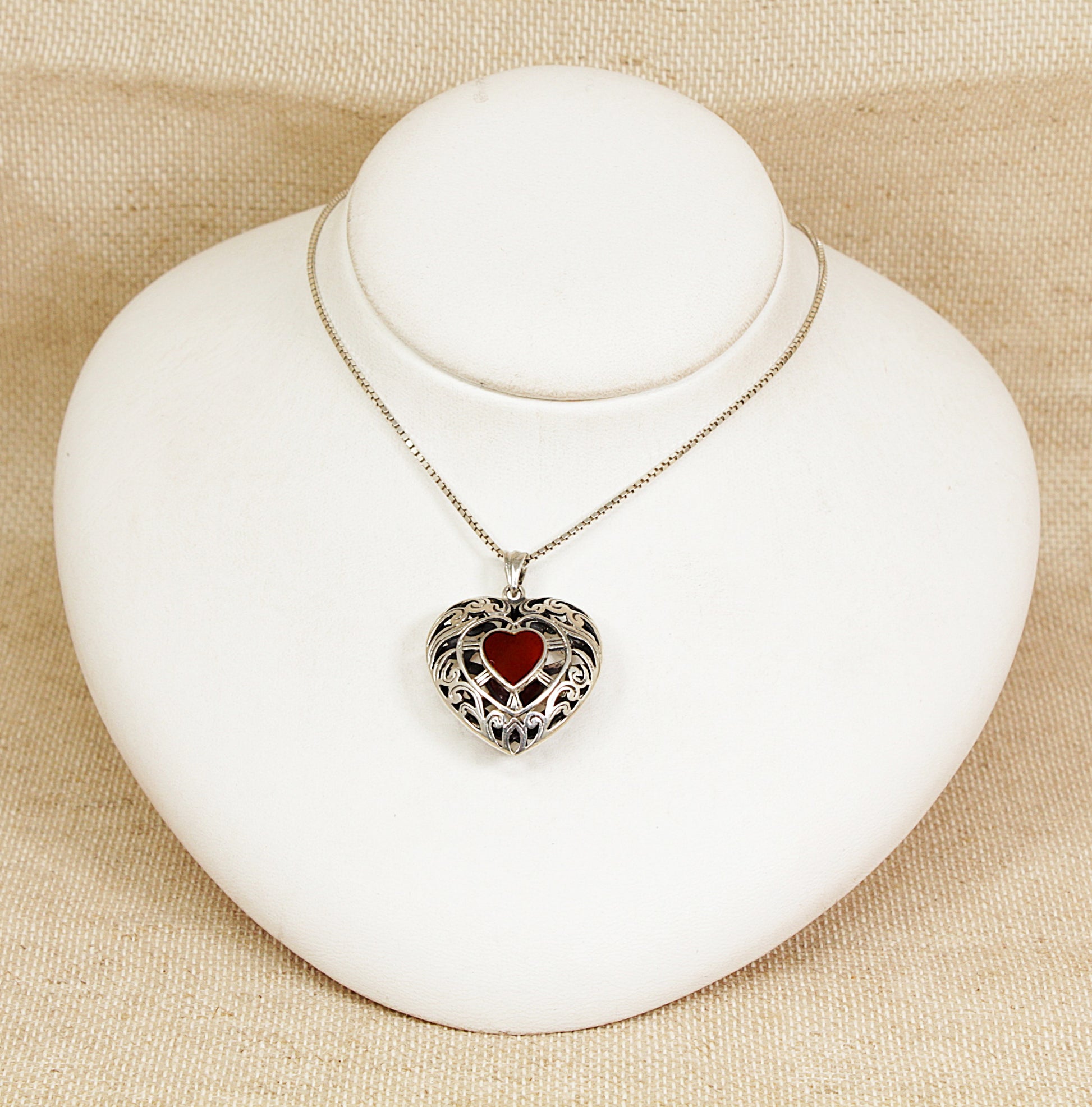 Heart-shaped pendant necklace on a white bust against a beige background