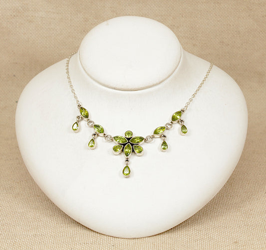 Silver Peridot necklace on a white mannequin bust against a beige background