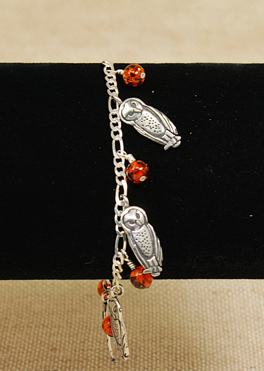 Bracelet with owl charms and red beads on a black and beige background