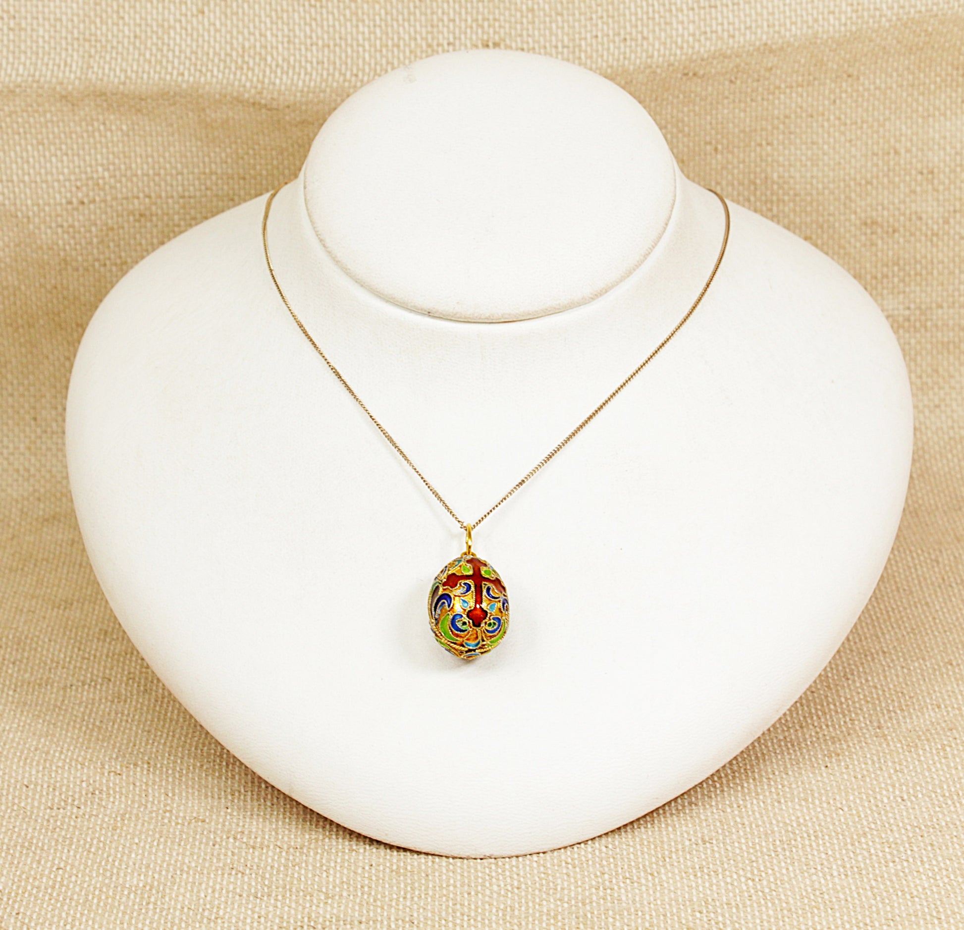Jewelry display with a necklace featuring a colorful pendant on a beige background