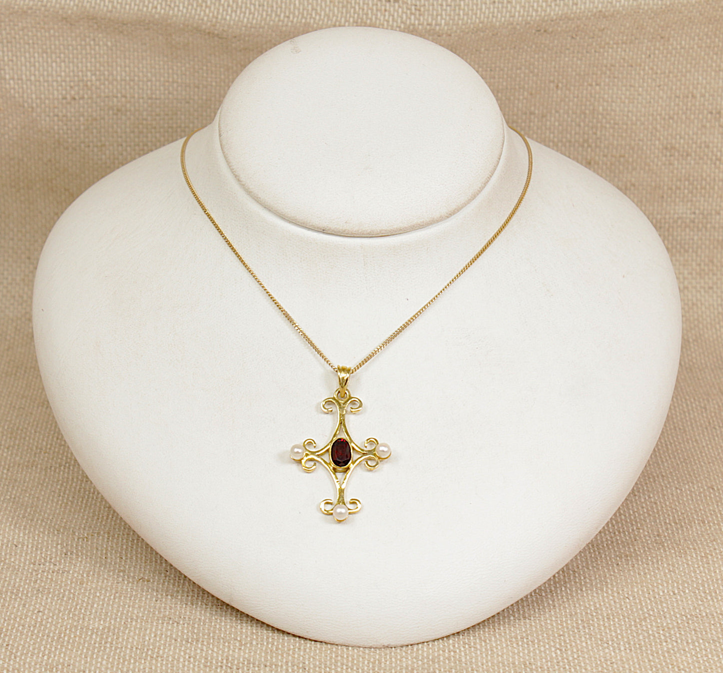 Gold necklace with a pendant on a white jewelry display