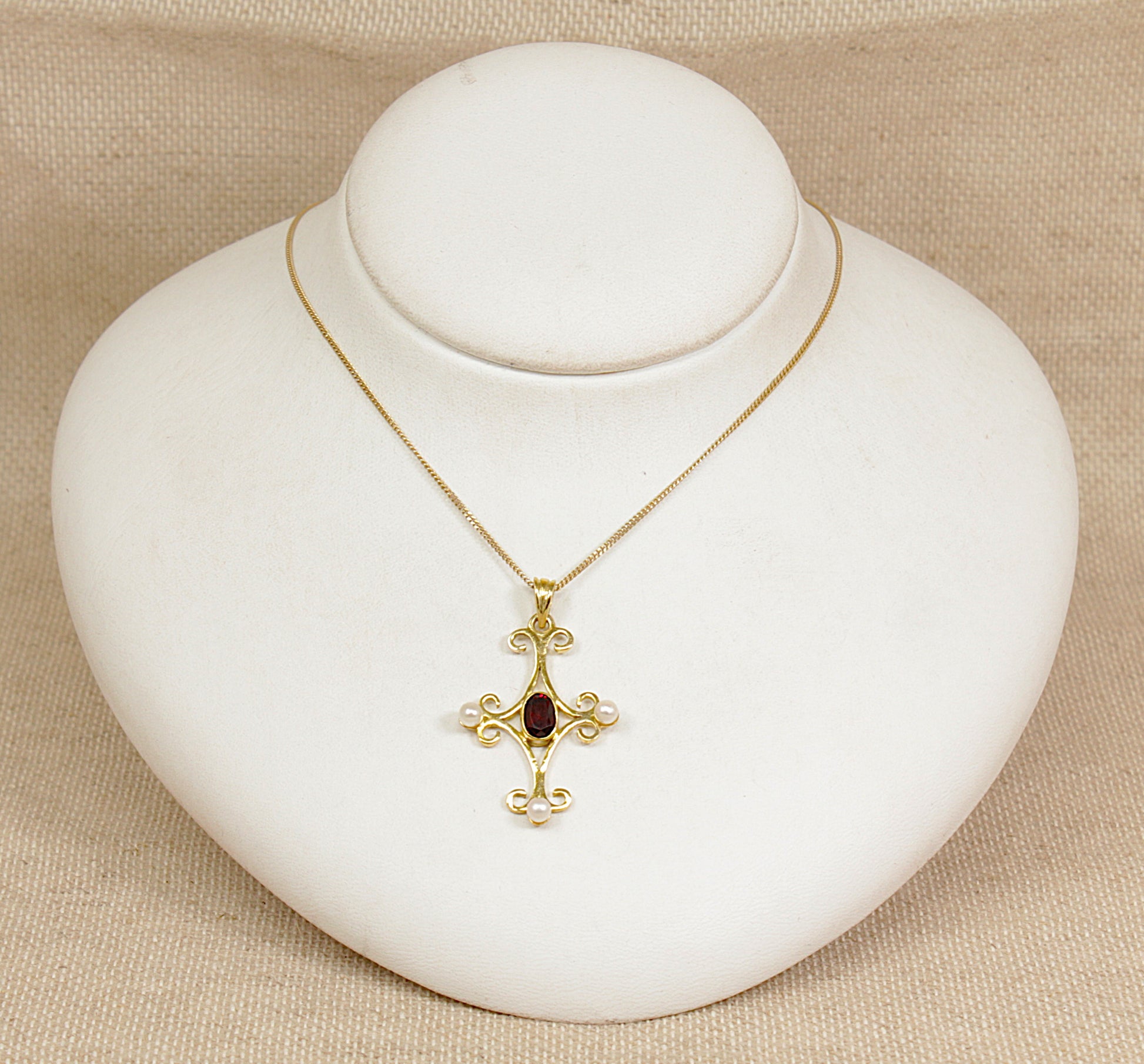 Gold necklace with a pendant on a white jewelry display