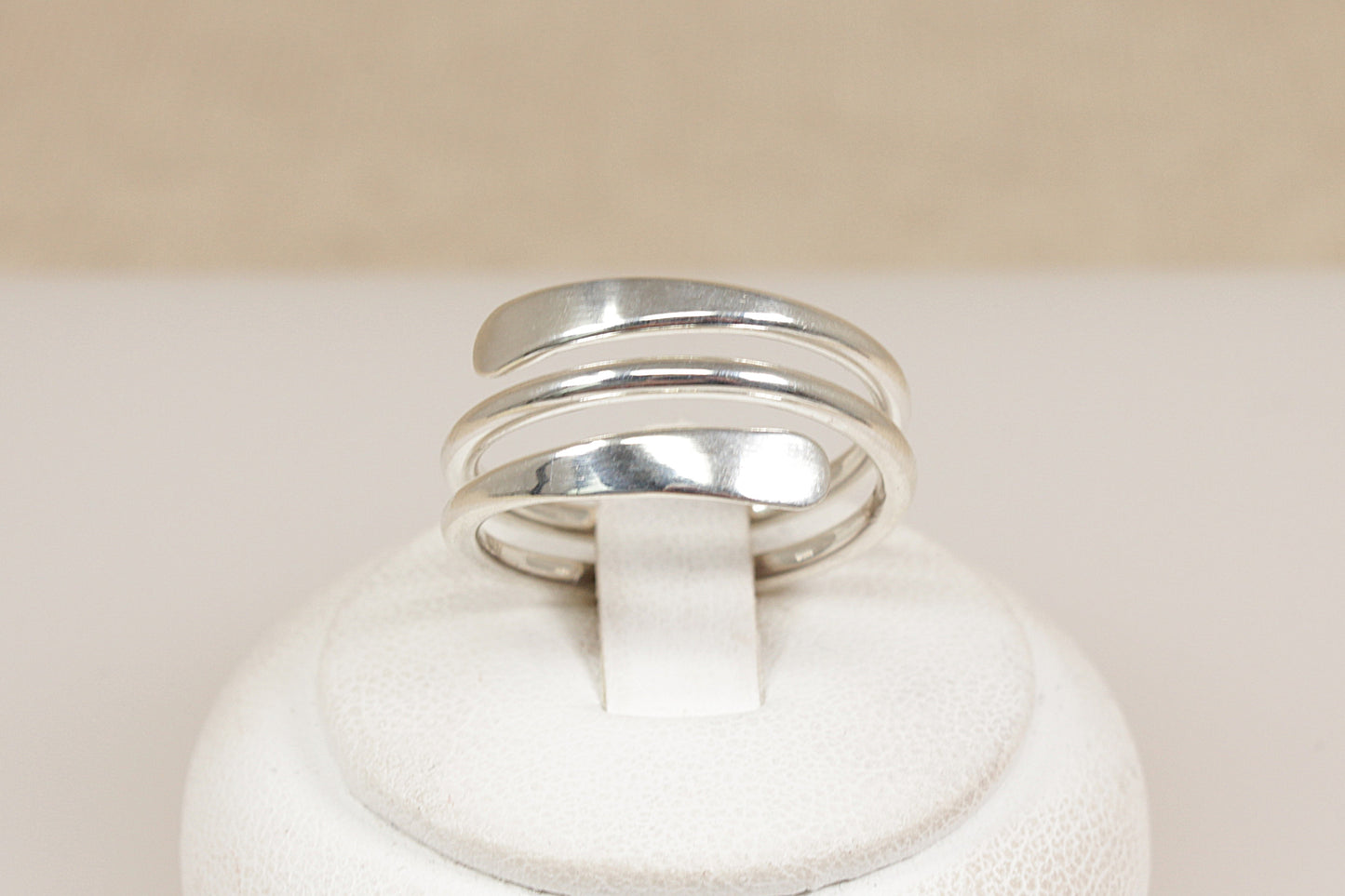 Silver coil ring on a white rind stand  with a beige background
