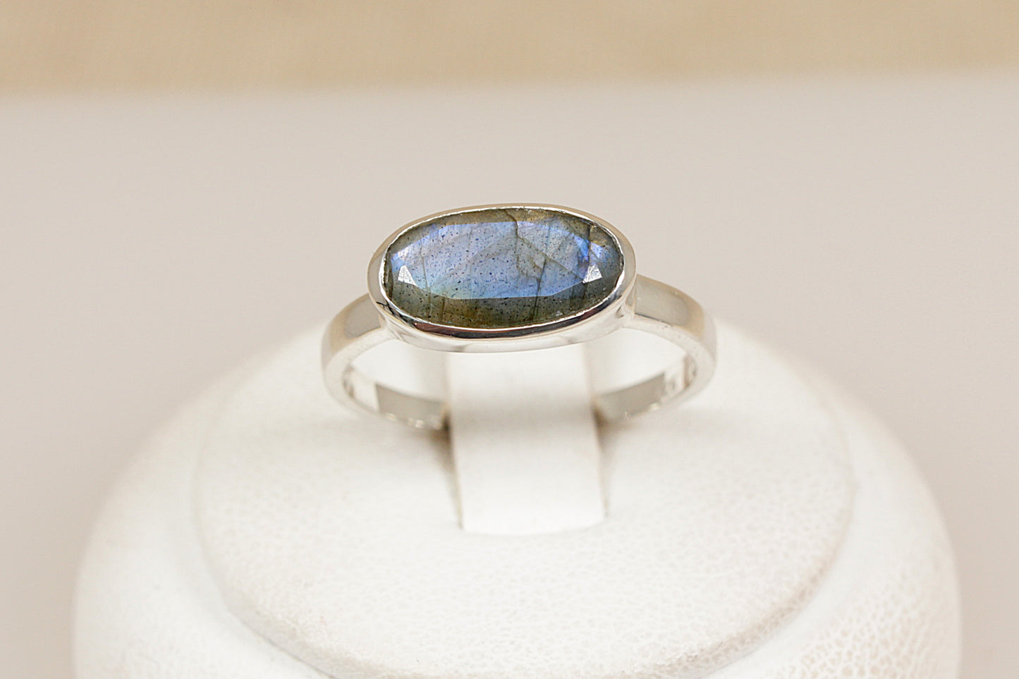 Silver ring with a labradorite gemstone on a white pedestal