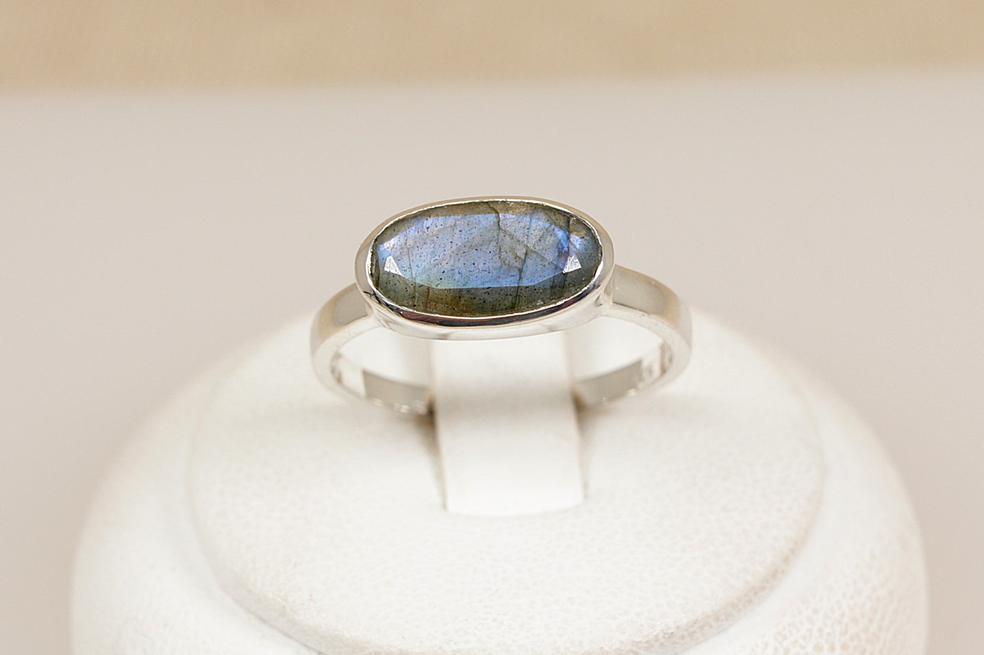 Silver ring with a labradorite gemstone on a white pedestal
