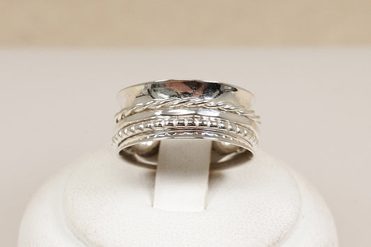 Silver ring with intricate design on a white cushion