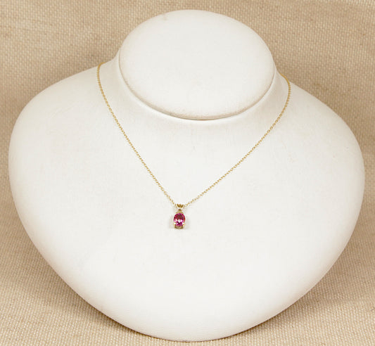 Gold necklace with a pink tourmaline pendant on a white mannequin bust against a beige background