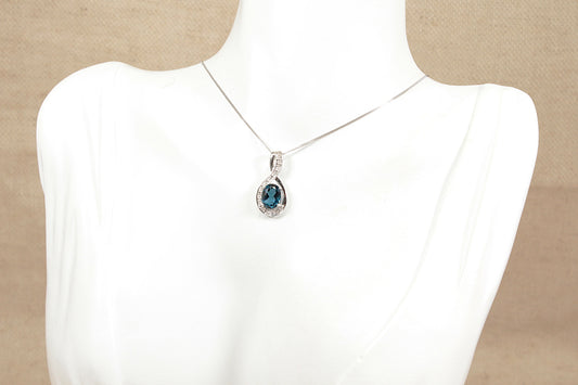 White gold necklace with a blue topaz gemstone pendant on a mannequin bust.