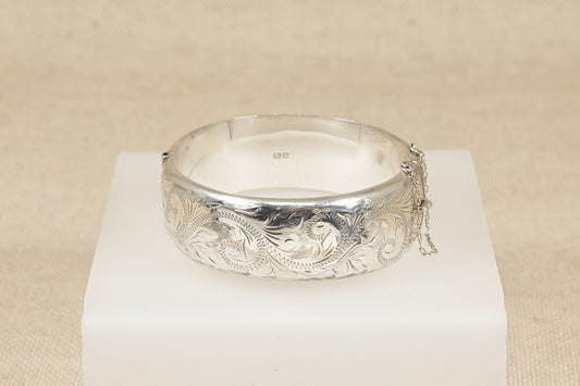 Silver bracelet with intricate designs on a beige background