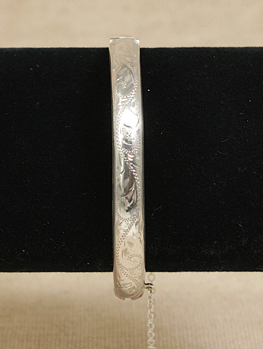 Vintage silver bracelet with intricate designs on a black velvet stand