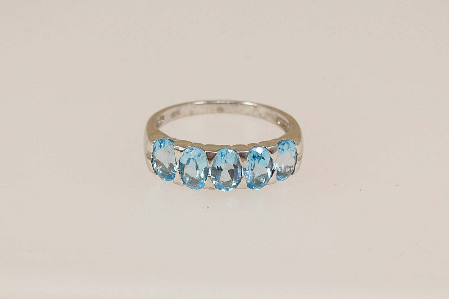 Silver ring with blue topaz gemstones on a beige background