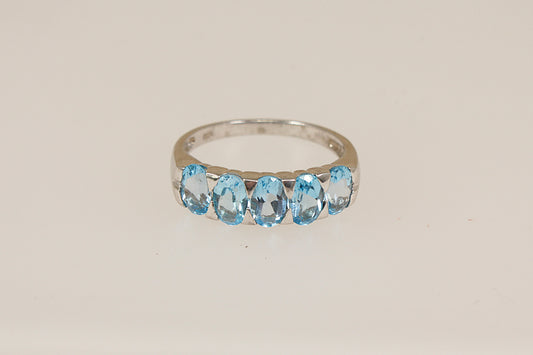 Silver ring with blue topaz gemstones on a beige background