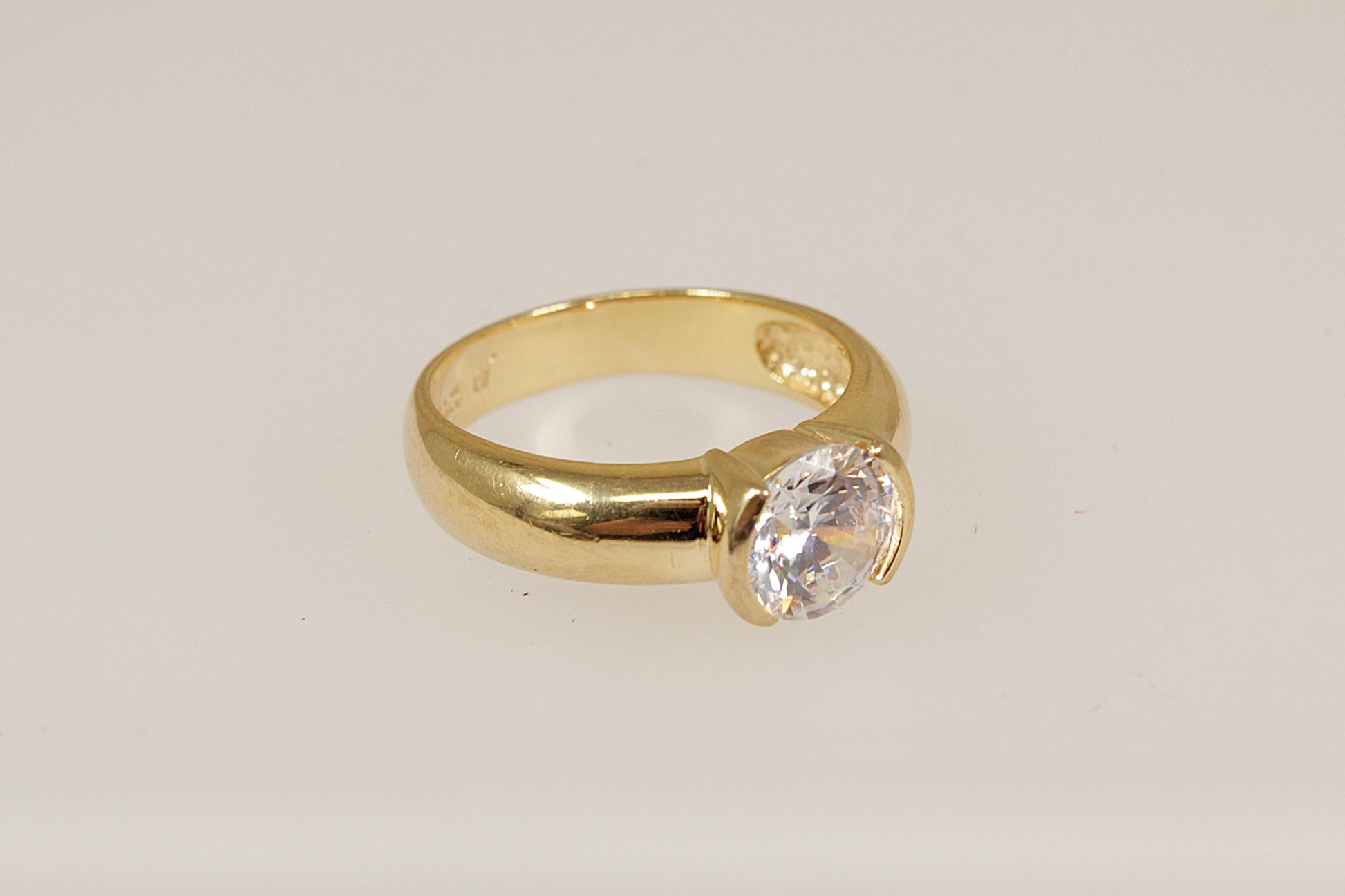 Silver gold plated ring with a c.z. diamond simulant gemstone on a light beige background