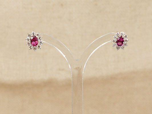 Pair of earrings with red almandine garnet gemstone surrounded by a halo of cz gemstones  on a beige background