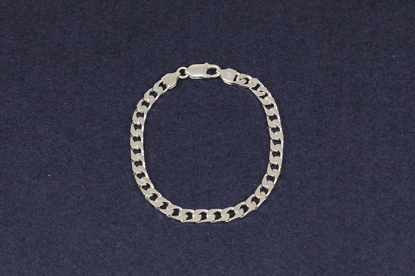 Ladies Gents Silver flat curb link  bracelet on a dark blue background