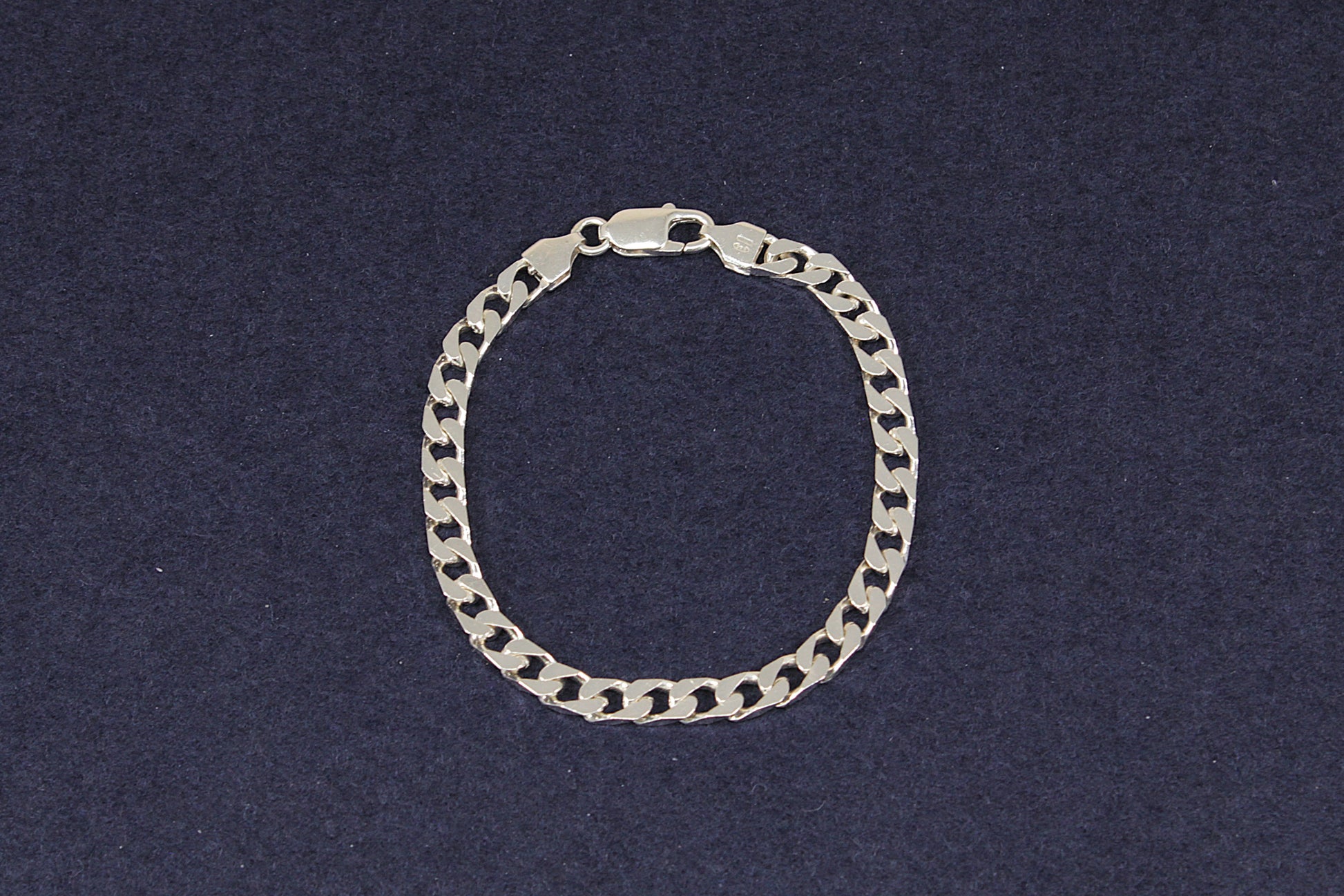 Ladies Gents Silver flat curb link  bracelet on a dark blue background