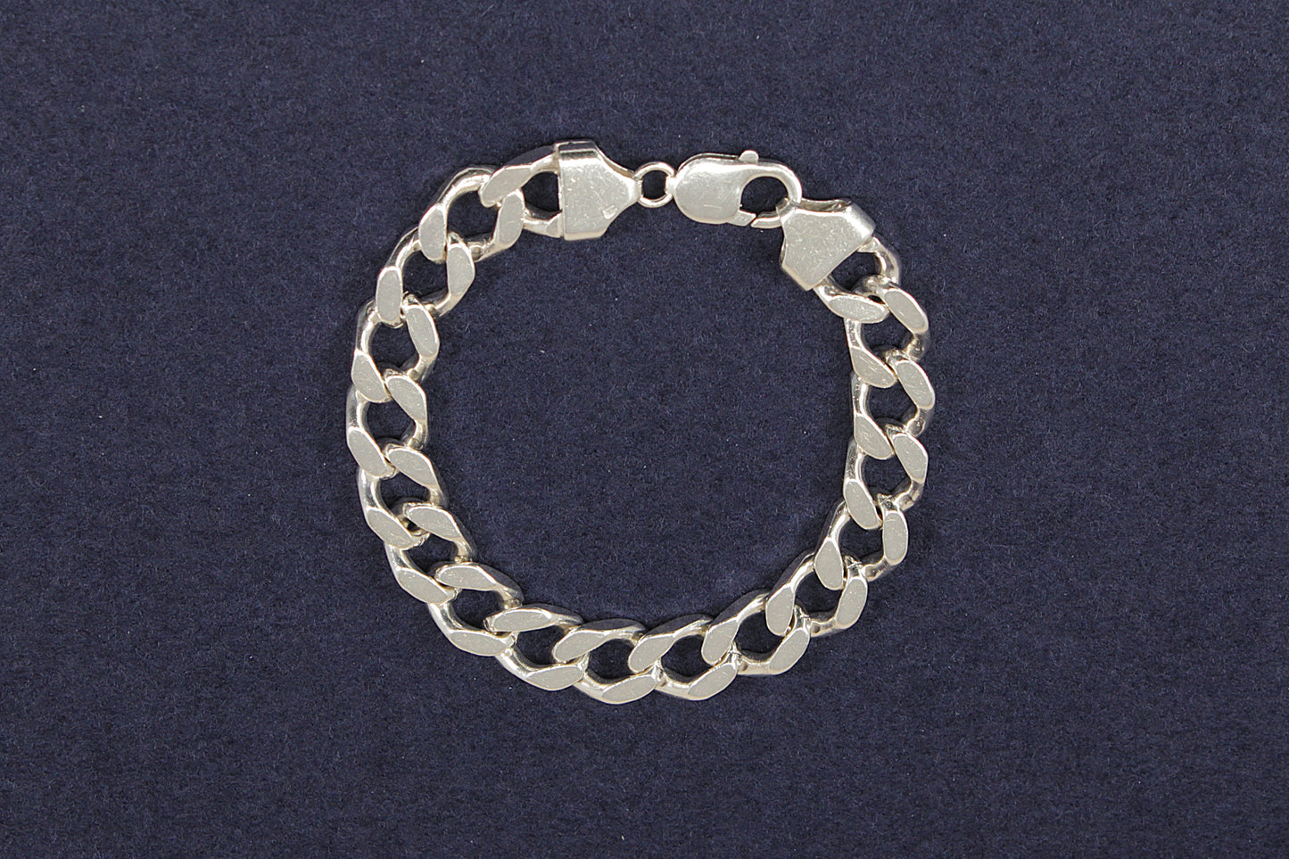Heavy gents silver curb link chain bracelet on a dark blue background