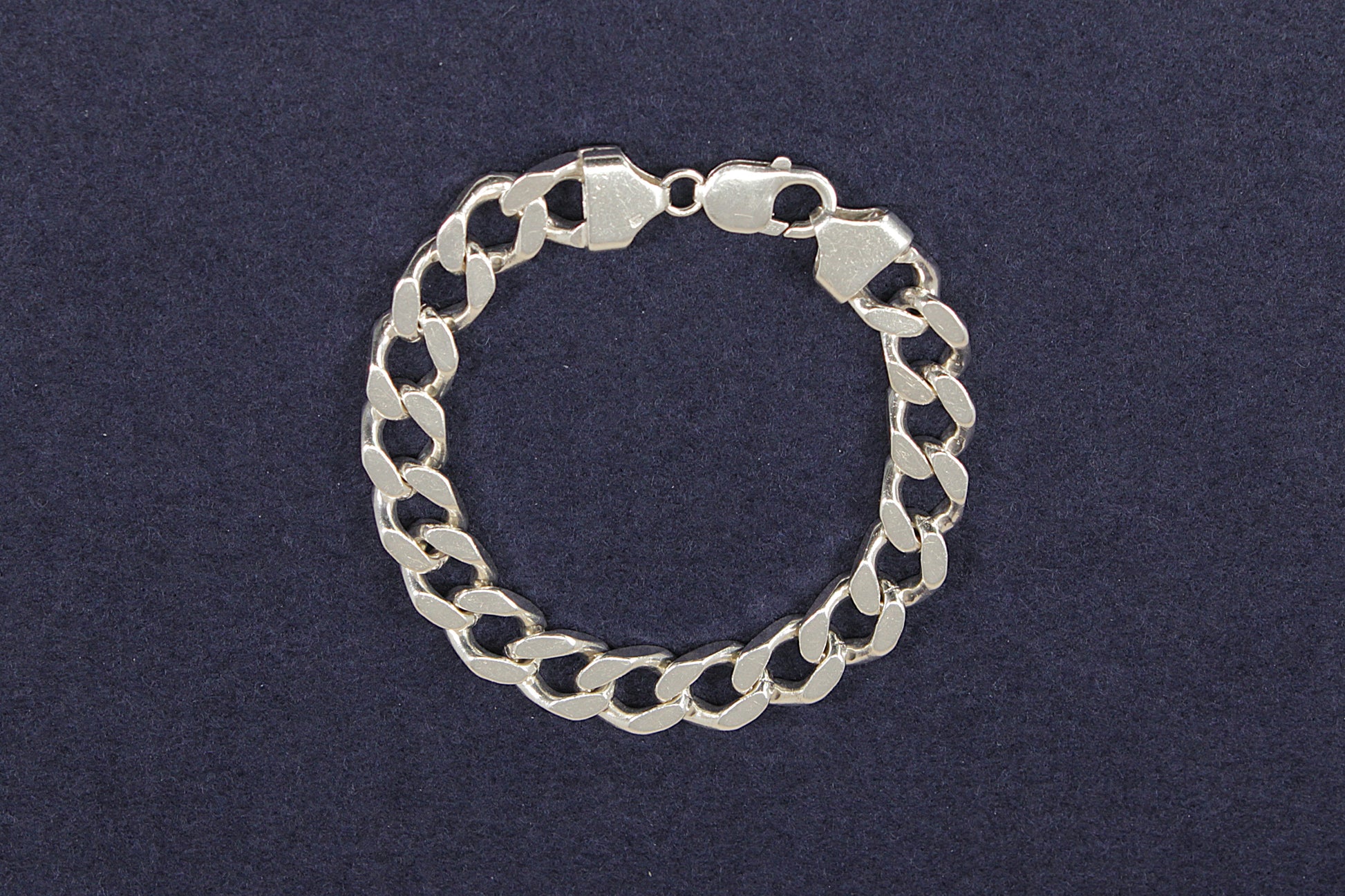 Heavy gents silver curb link chain bracelet on a dark blue background