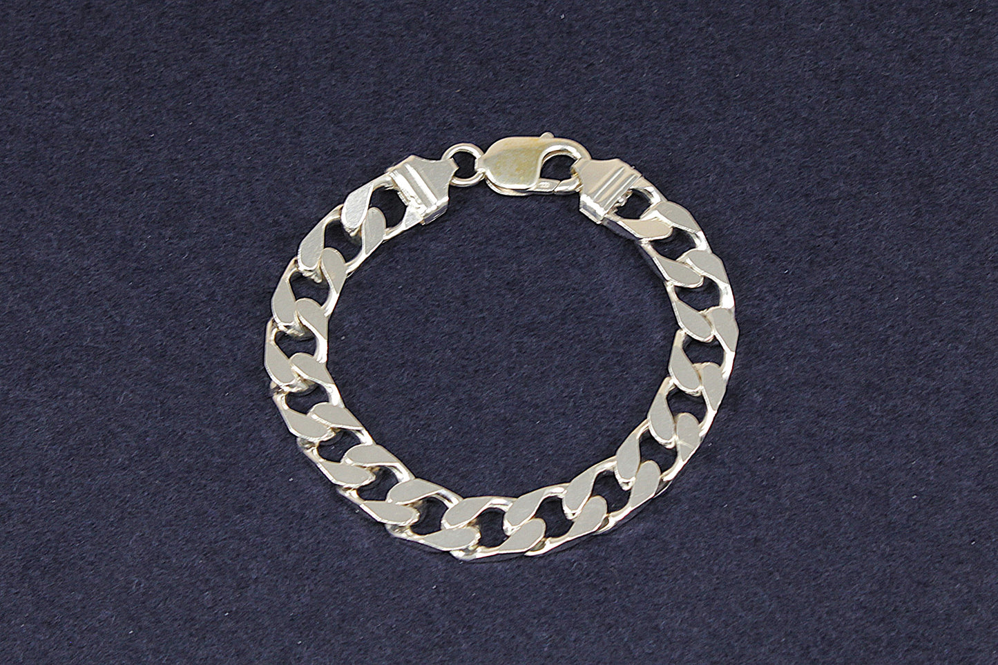Gents Ladies Silver flat curb link chain bracelet on a dark blue background