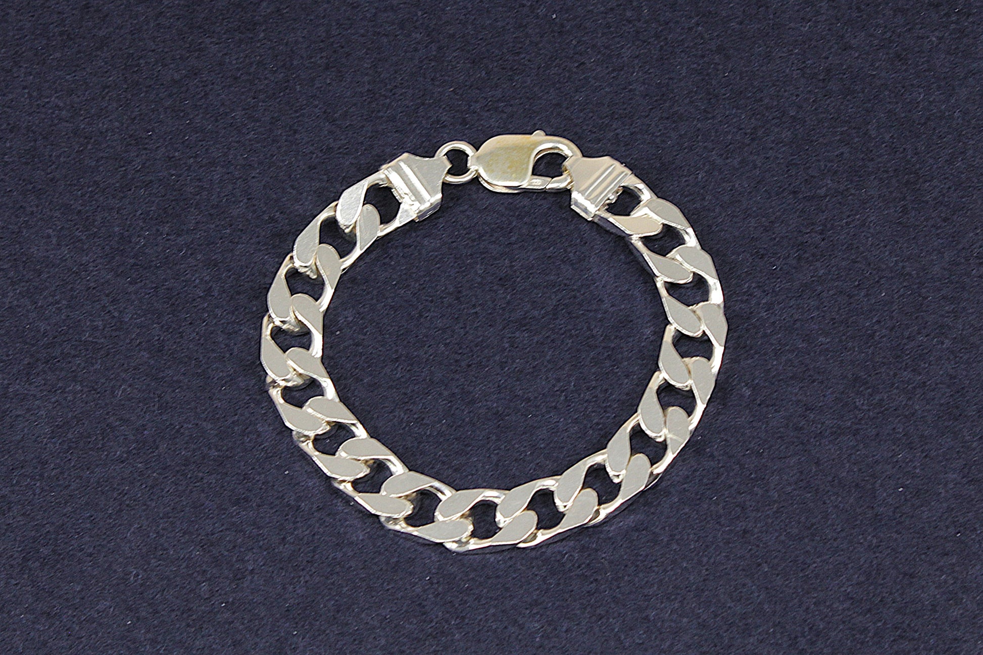Gents Ladies Silver flat curb link chain bracelet on a dark blue background