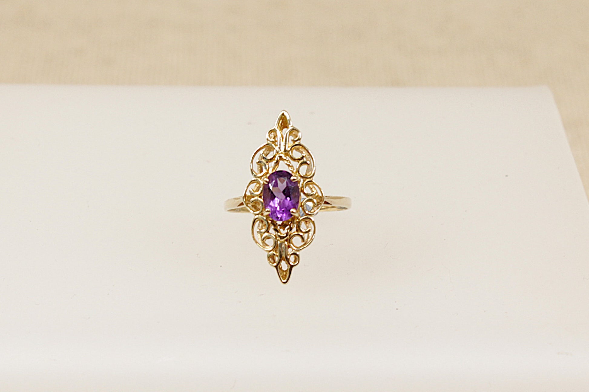 A 9ct gold ornate navette-shaped ring with a deep purple oval Amethyst gemstone, It is in excellent condition and inside the band it has Sheffield Hallmarks for 9ct gold. UK Finger size O.