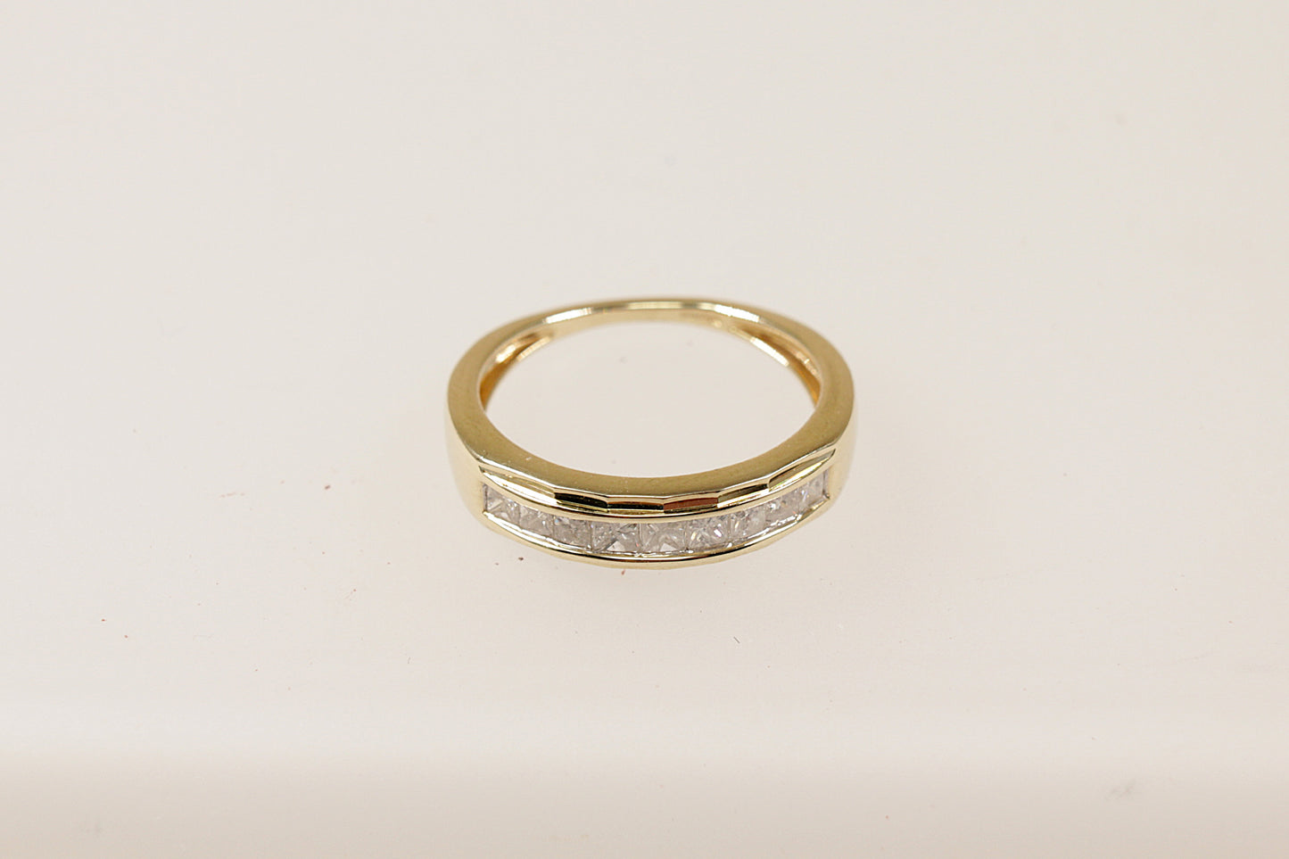 A 9ct gold band ring with channel-set princess cut diamonds around the middle section, The ring is in excellent condition and inside the band it has Birmingham hallmarks and the makers mark CR. UK Finger size N. 