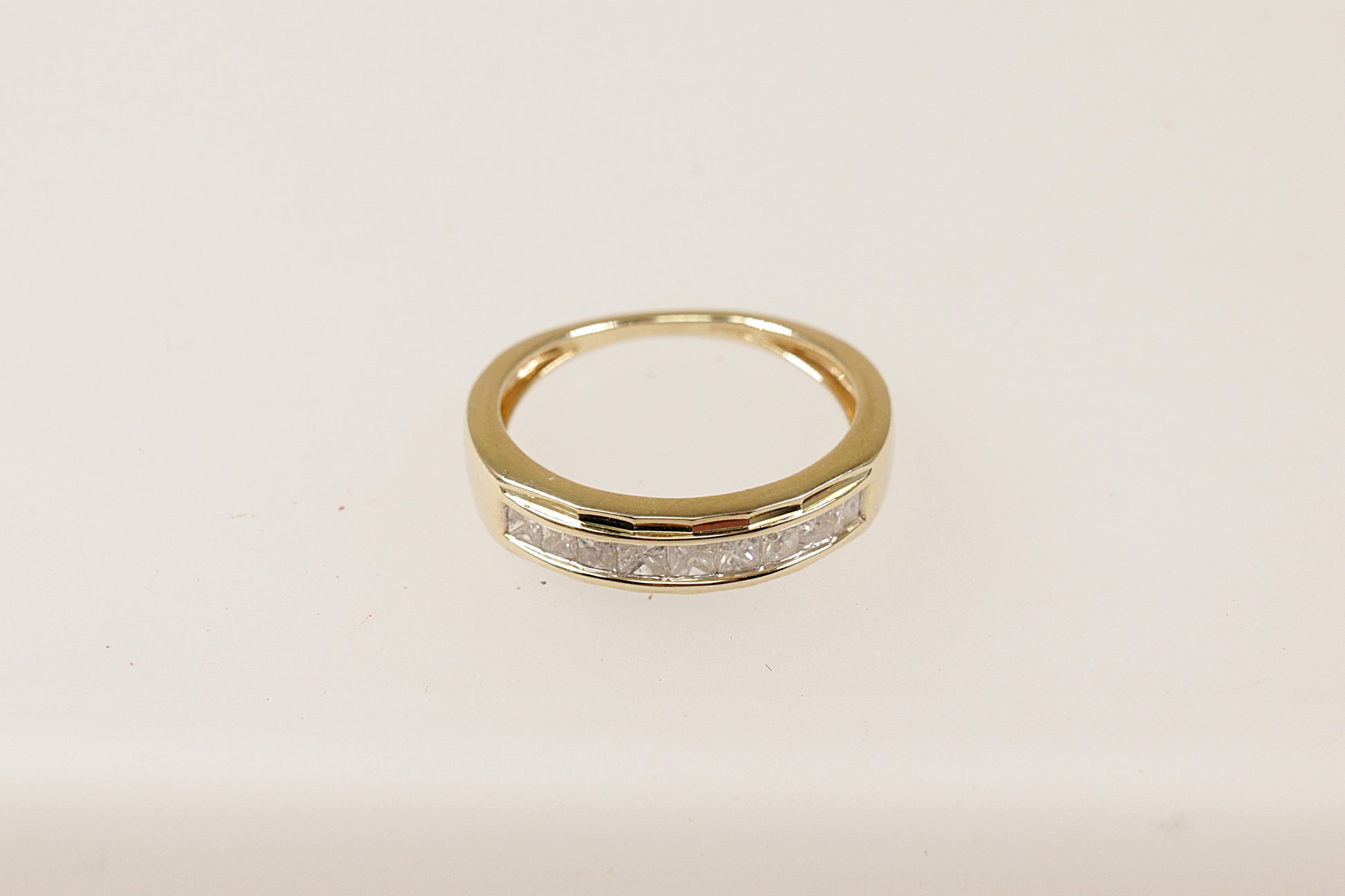 A 9ct gold band ring with channel-set princess cut diamonds around the middle section, The ring is in excellent condition and inside the band it has Birmingham hallmarks and the makers mark CR. UK Finger size N. 