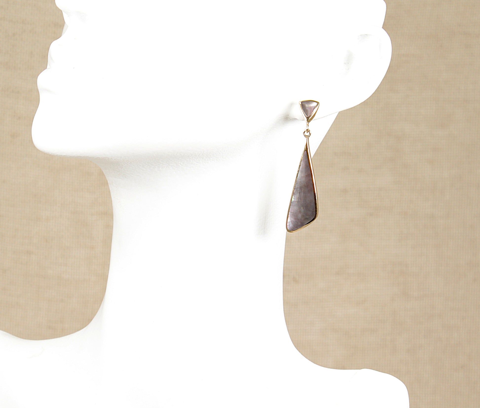 A pair of 9ct gold dropper earrings with abalone shell inlays displayed on a mannequin head.