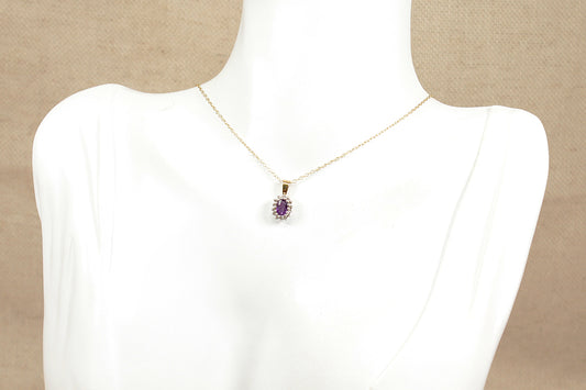 A gold amethyst and diamond pendant necklace on a white bust