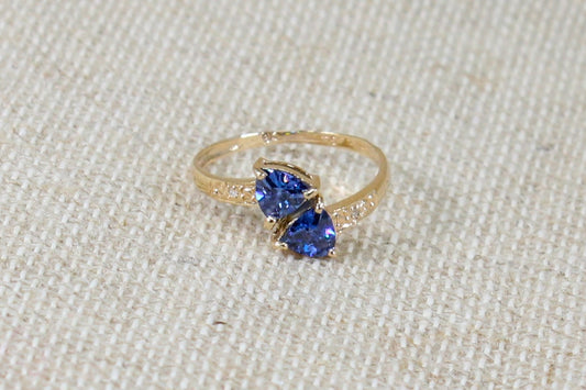 This stunning ring has 2 trillion cut Blue Iolites off set in a handcrafted 3 claw setting on each gemstone. On the shoulders are clear Cubic Zirconia accent gemstones. A pretty ring in excellent condition made in the traditional richness of 9ct yellow gold.
The band on the inside is stamped 9k 375. UK Finger size O.