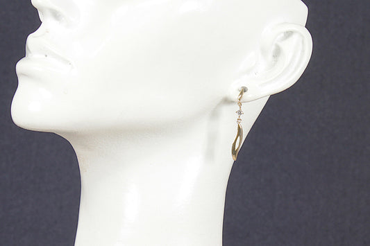 Gold and crystal earrings on a white mannequin head against a dark background