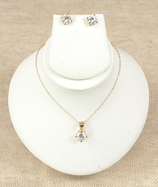 Gold pendant necklace and gold earrings jewellery set on a white display bust.