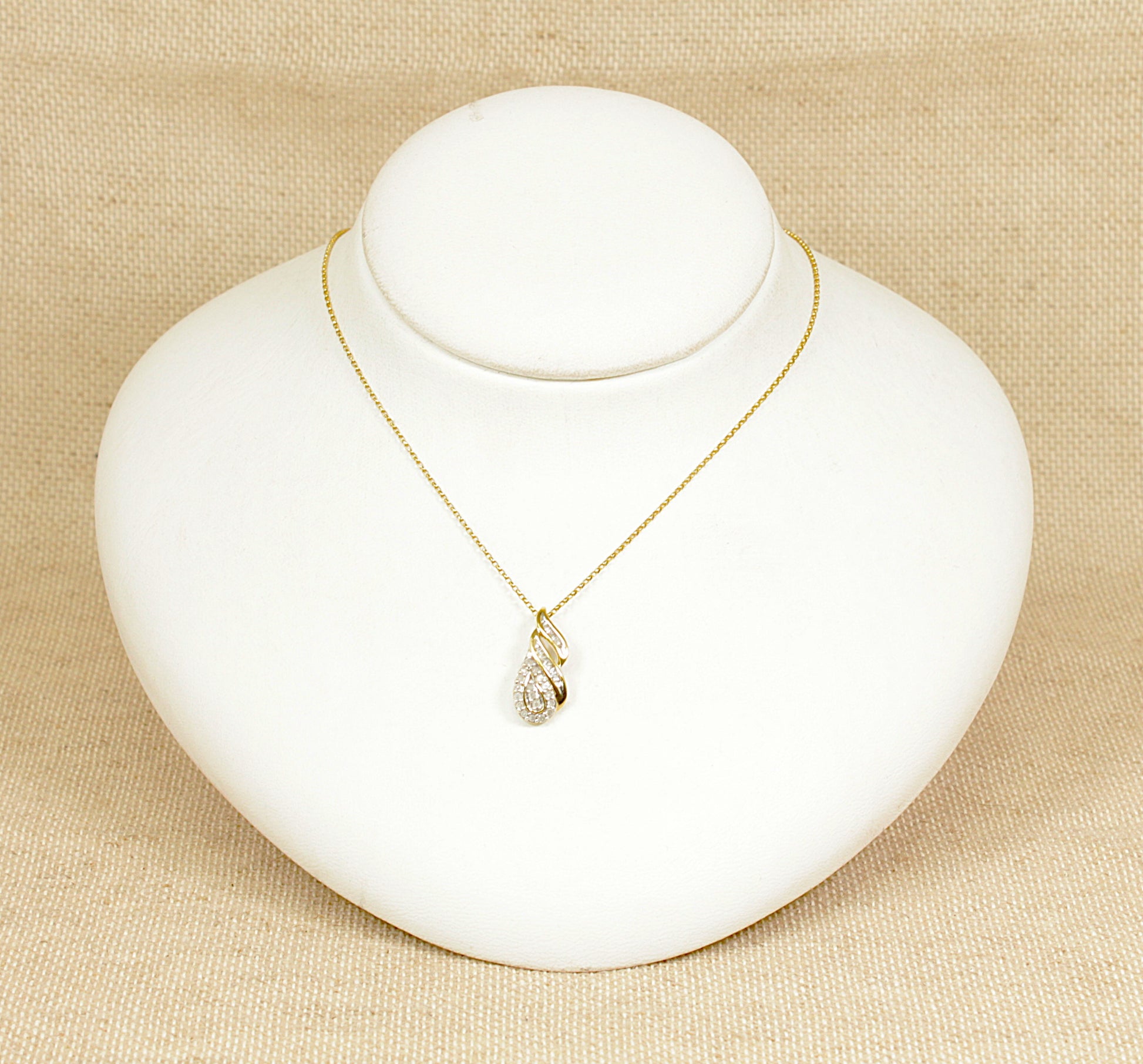 A very attractive 9ct yellow gold diamond cluster pendant, designed in an overall pear shape. The pendant features two slanted rows of baguette-cut diamonds leading to a pear-shaped cluster of 18 round brilliant-cut diamonds, securely claw-set for maximum sparkle. The pendant is suspended from an 18-inch 9ct gold belcher-style chain.