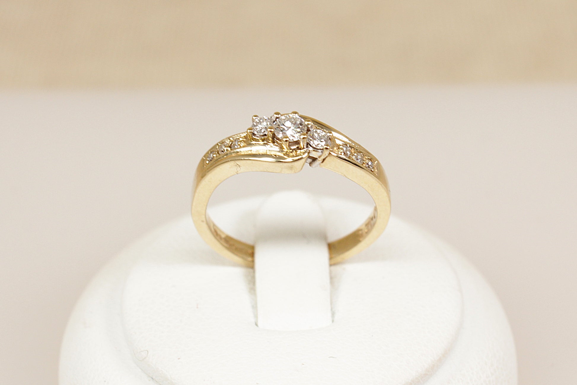 A timeless and graceful 9ct gold Diamond ring, featuring a classic trilogy twist design. At its centre are three sparkling diamonds set in a gentle twist, symbolizing the past, present, and future. Each shoulder is adorned with three smaller diamond accents, adding extra brilliance and elegance to the design, UK finger size N.