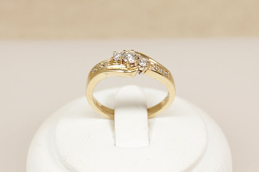 A timeless and graceful 9ct gold Diamond ring, featuring a classic trilogy twist design. At its centre are three sparkling diamonds set in a gentle twist, symbolizing the past, present, and future. Each shoulder is adorned with three smaller diamond accents, adding extra brilliance and elegance to the design, UK finger size N.