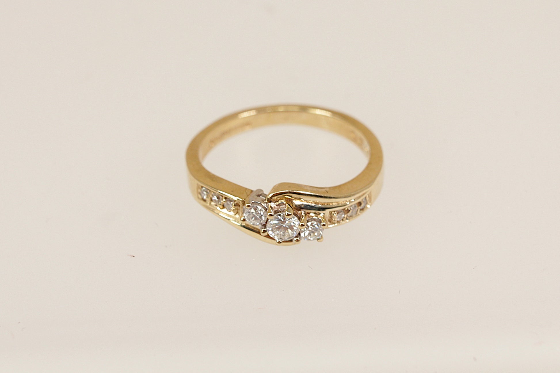 Gold ring with three centre diamonds on a beige background