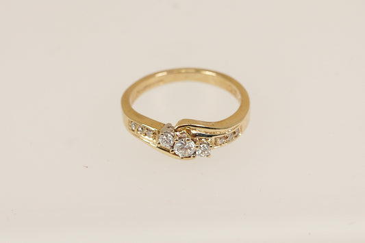 Gold ring with three centre diamonds on a beige background