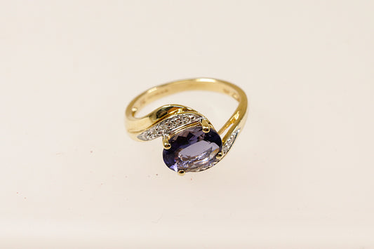 This 9ct Gold ring is a perfect blend of classic and contemporary design. The combination of the rich Iolite, shimmering Diamond accents, and the fluid twist design creates a piece that feels both timeless and distinctive. The centrepiece is the oval Blue Iolite that is claw set across the setting that gives a modern touch to the classic twist design. The Diamond accents are set along the twist. UK finger size M.