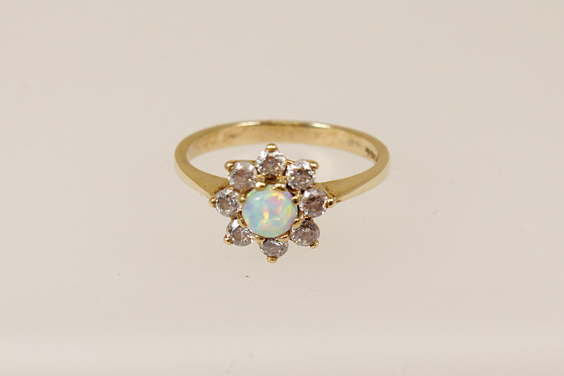 A 9ct gold daisy ring with a central opal surrounded by white crystals, displayed against a white background.