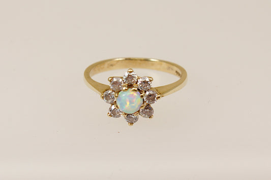 A 9ct gold daisy ring with a central opal surrounded by white crystals, displayed against a white background.