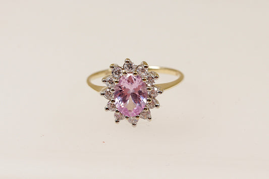A 9ct gold ring with an oval pink sapphire centerpiece and a halo of round-cut cubic zirconia around it.
