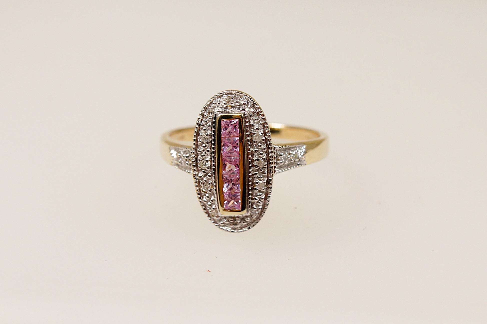 A 9ct gold ring with a vertical arrangement of pink sapphire stones and diamond accents around the oval design and on the shoulders.