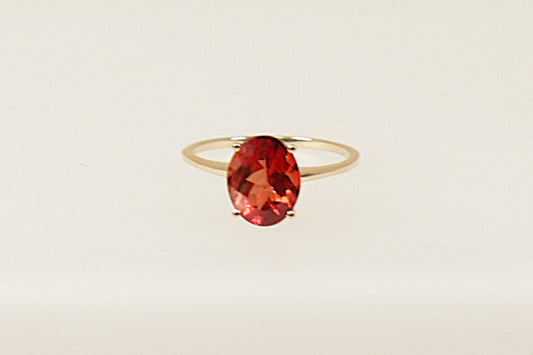 A 9ct gold solitaire ring with an oval rhodolite garnet colored crystal, displayed against a white background.