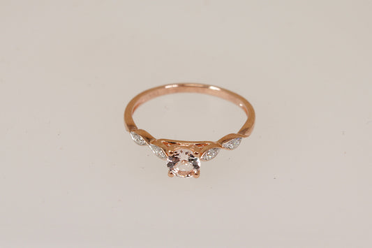 Rose gold ring with a central morganite gemstone and smaller diamond gemstones on a light beige background