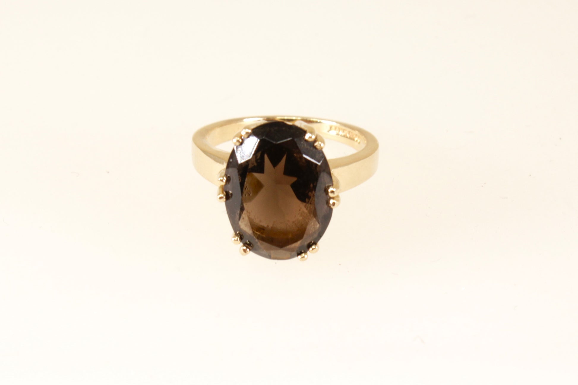 A 9ct gold solitaire ring with a smokey quartz oval stone, displayed against a white background.