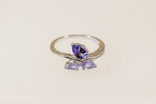A 9ct white gold ring with three pear cut blue iolite gemstones arranged in an offset pattern to form the petals of a flower.