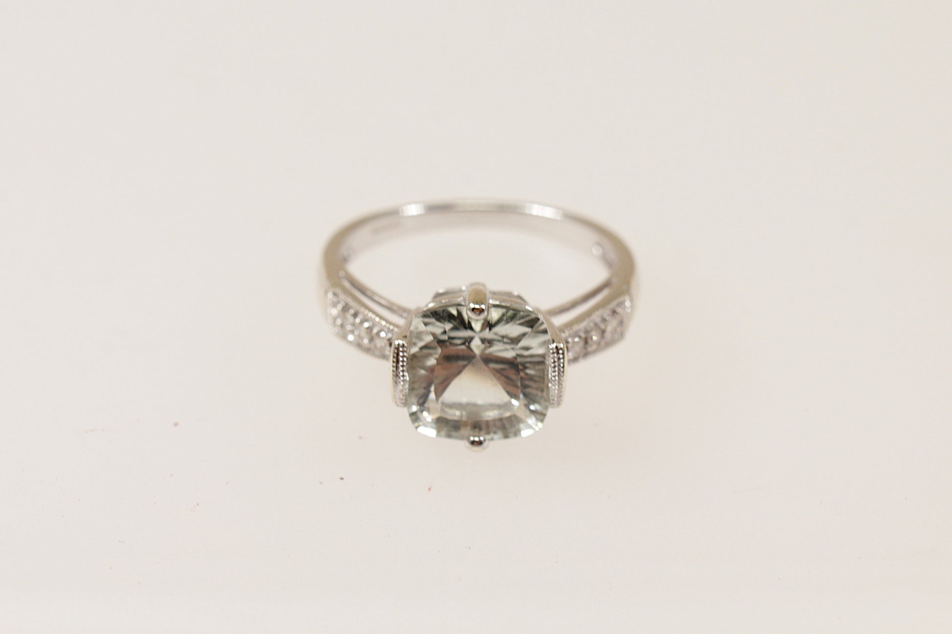 A 9ct White Gold large cushion cut pale green Citrine, Each shoulder has 3 Diamond accents, enhancing the ring’s brilliance, inside the band it has Birmingham hallmarks for 2008, UK Finger size: O.