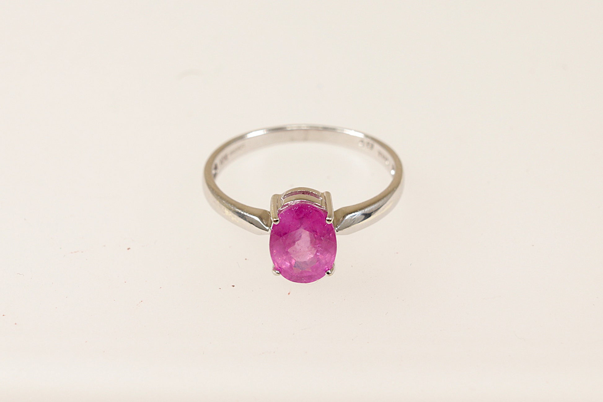 A 9ct white gold ring with an oval pink Sapphire centerpiece, displayed against a white background.